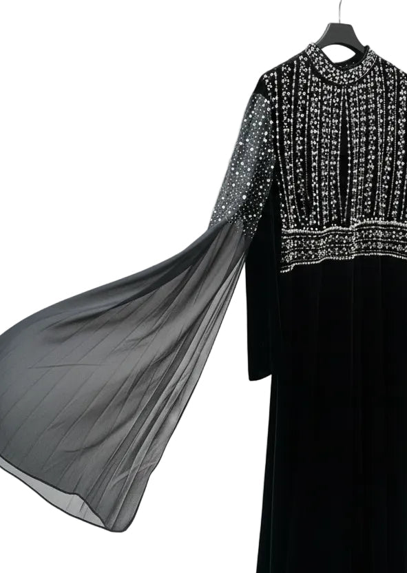 Black dress on a hanger with a blurred indoor background