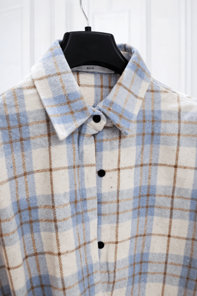 Plaid shirt on a hanger against a white background