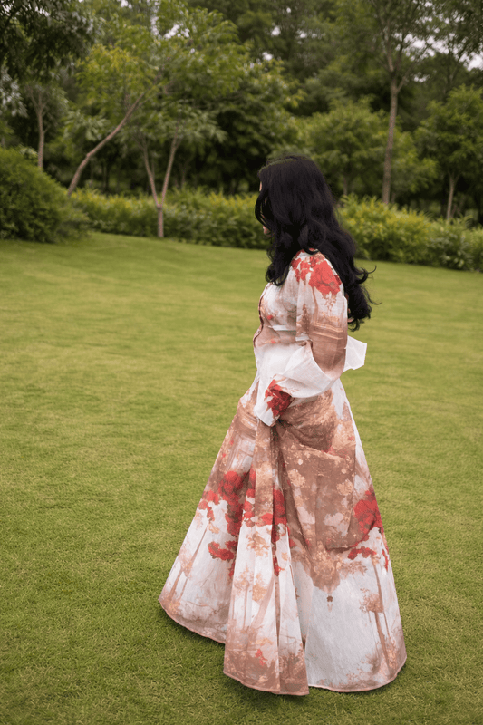 Woman in a floral dress standing on grass with trees in the background