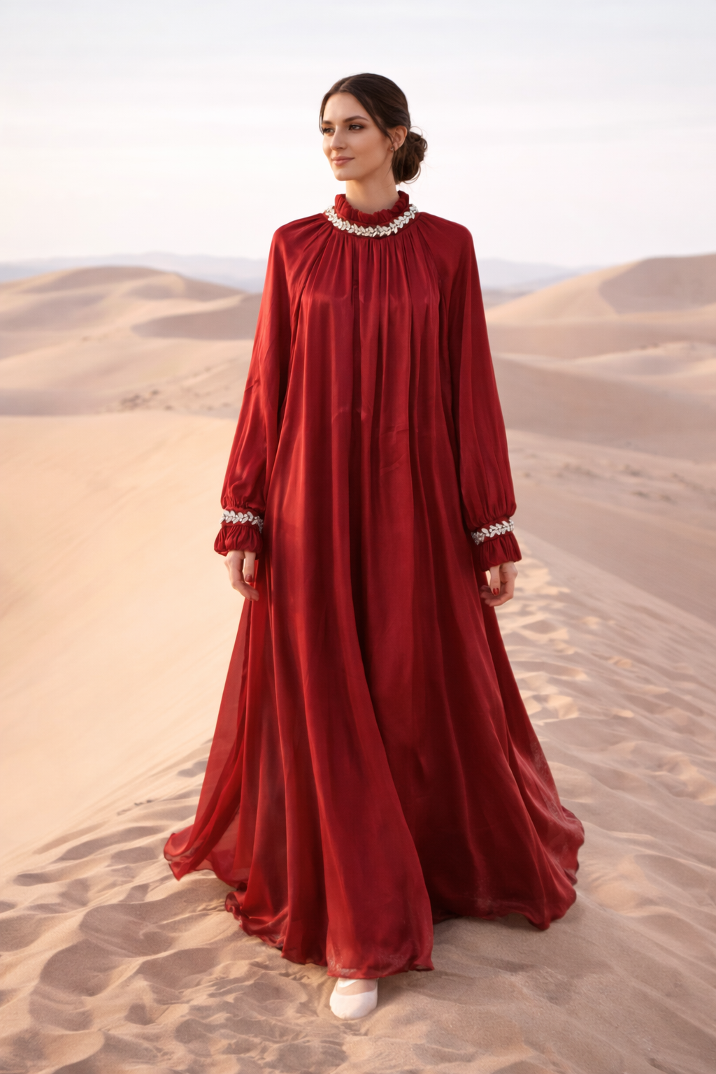 Woman in a red dress standing in desert sand dunes