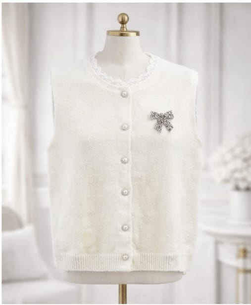 White cardigan with a decorative bow on a mannequin against a white background