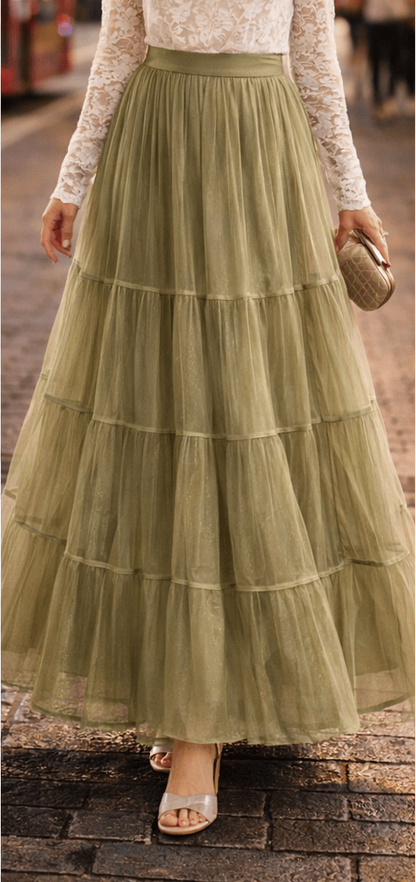 Woman wearing a long, light green tiered skirt with a white lace top on a city street.