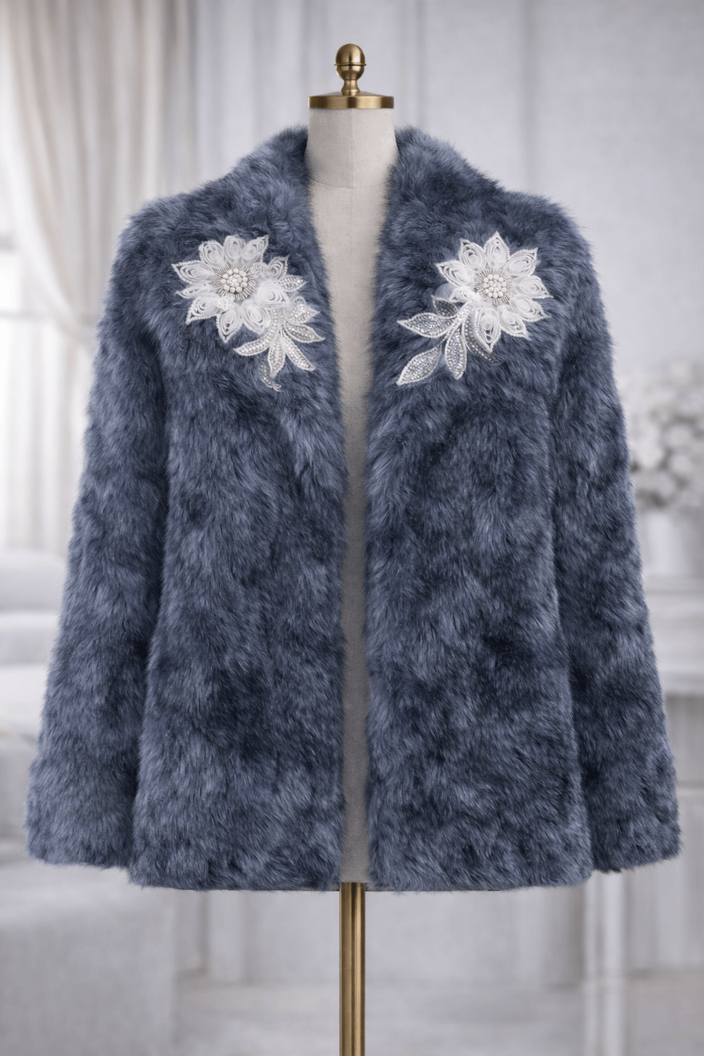 Blue fuzzy coat with floral embellishments on a mannequin against a neutral background