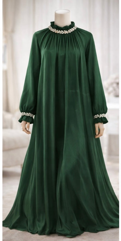 Green dress with pearl embellishments on a mannequin against a neutral background