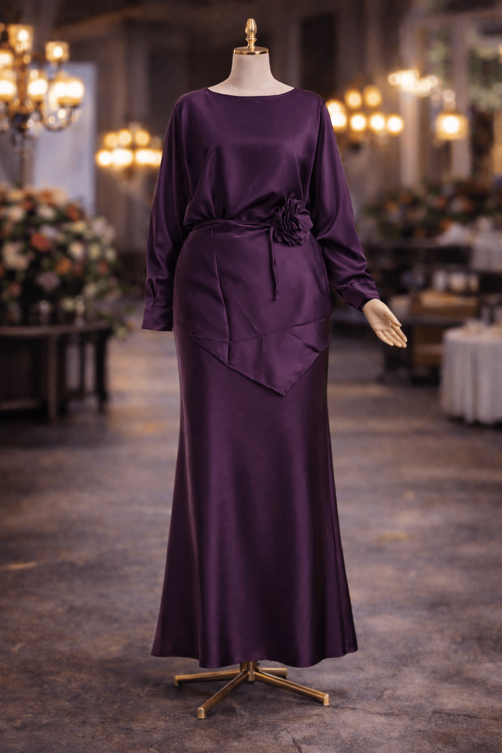 Purple evening gown on a mannequin in an elegant indoor setting with chandeliers.