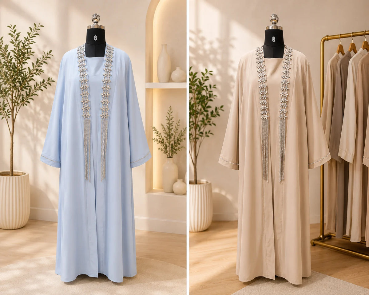Two abayas, one light blue and one beige, on mannequins with decorative elements in a well-lit room.