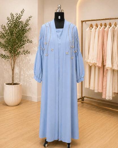 Light blue dress on a mannequin with a plant and clothing rack in the background