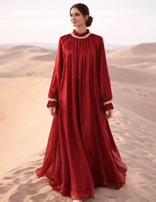 Woman in a long red dress standing on sand dunes