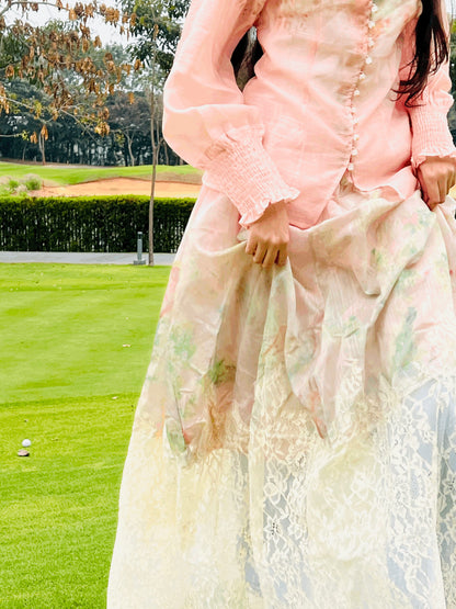 Person wearing a light pink floral dress with a blurred golf course background
