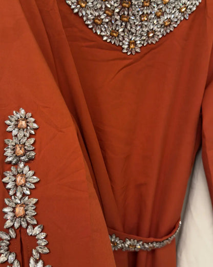 Close-up of a rust-colored garment with floral embellishments.